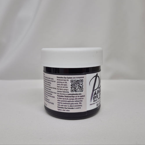 A small plastic jar of black liquid with a white screw cap, showing the side label with information on Paintables Dye System, set against a draped white fabric background.