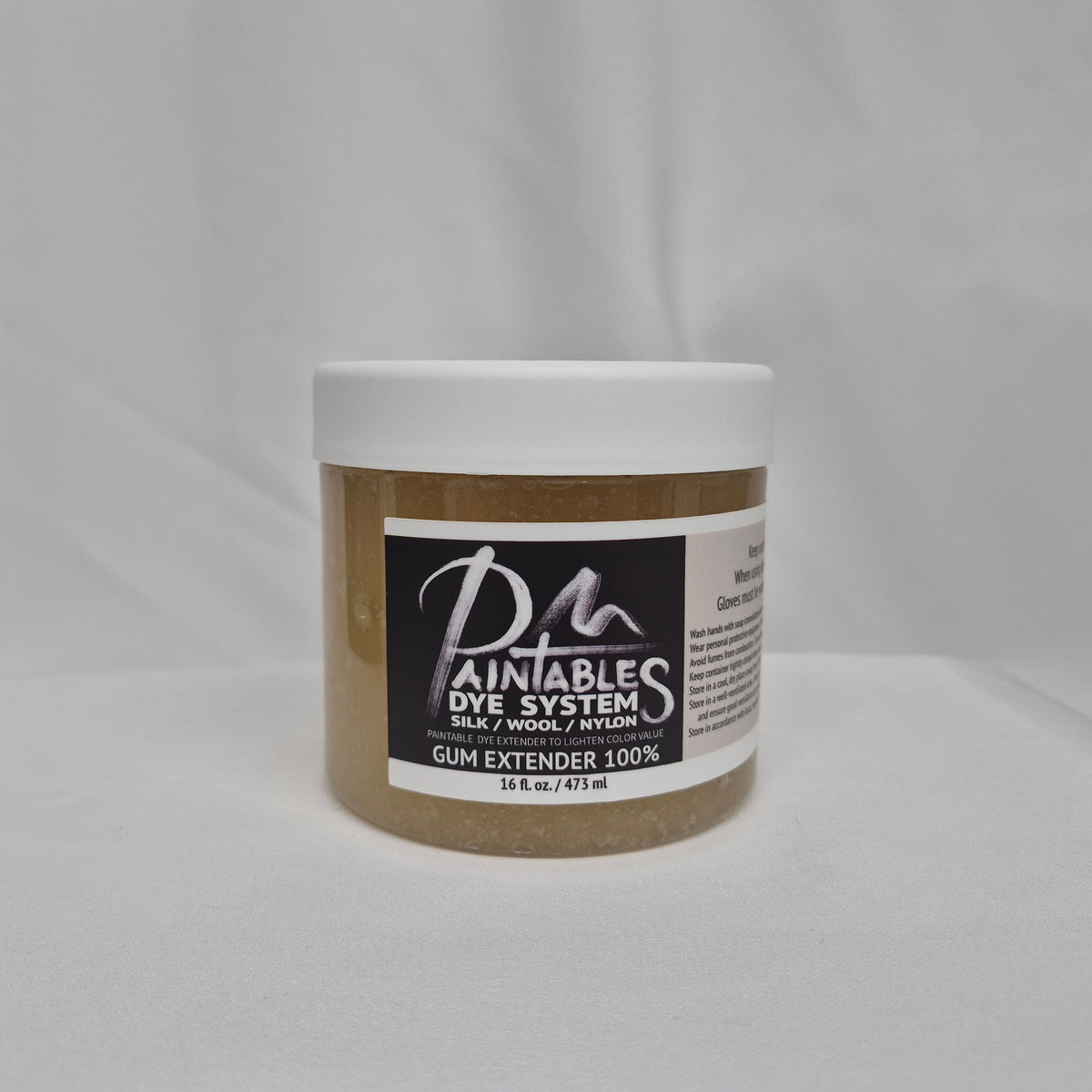 A 16oz white plastic jar of Paintable Dye System Gum Extender 100% on a white fabric background.