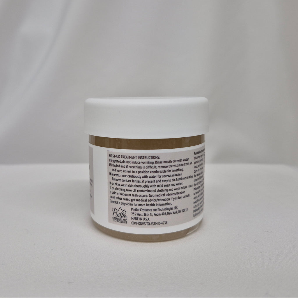 A small white plastic jar with a gum extender thickener inside, a white lid, and black label featuring black text containing first-aid instructions, set against a draped white fabric background.