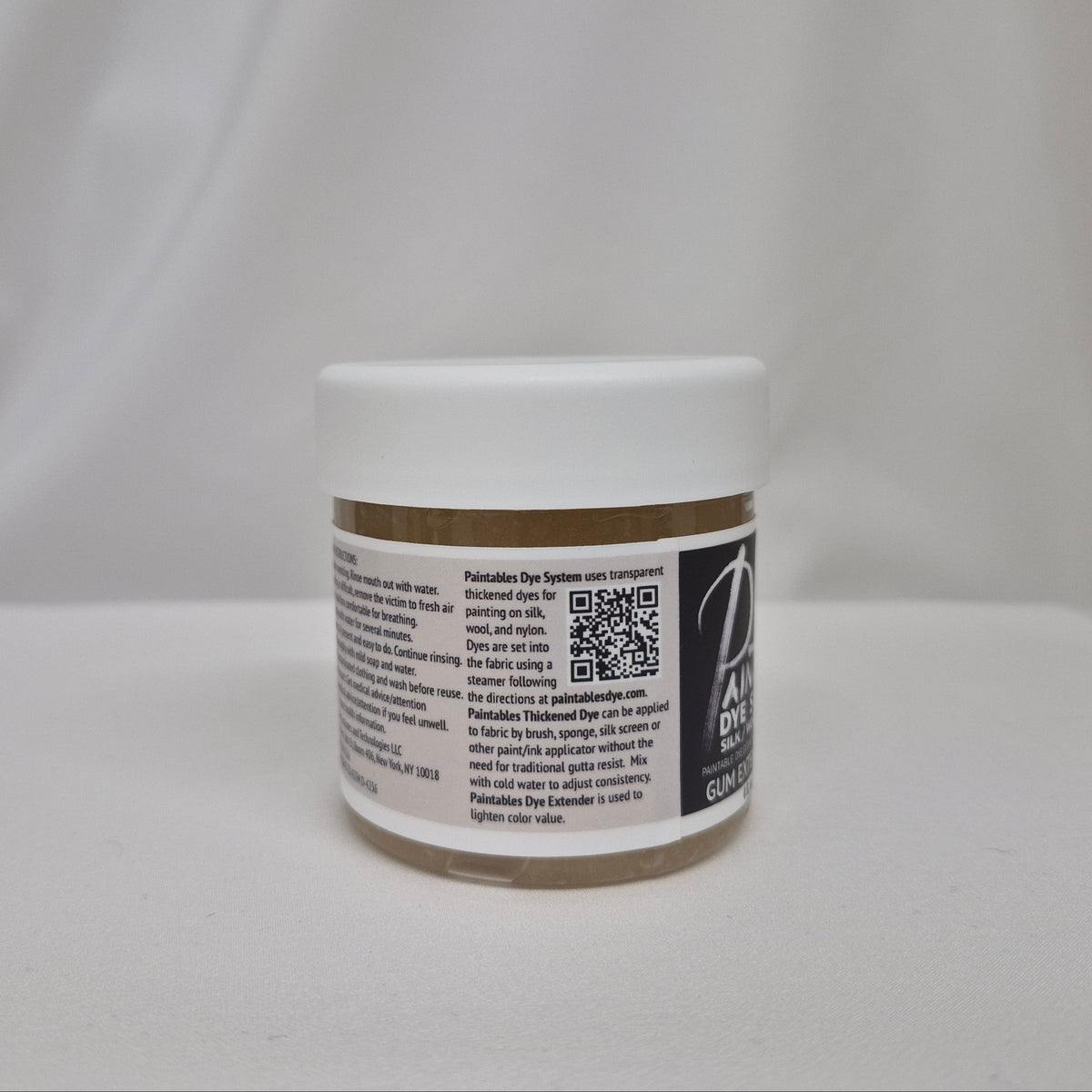 A small white plastic jar with a gum extender thickener inside, a white lid, and black label featuring black text and a QR code, set against a draped white fabric background.