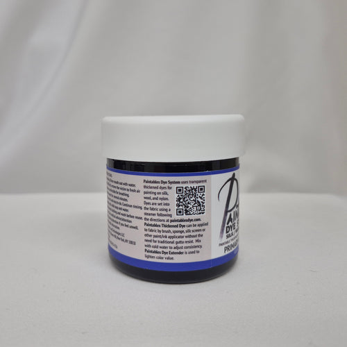 A small plastic jar of deep blue liquid with a white screw cap, showing the side label with info on Paintables Dye System, set against a draped white fabric background.