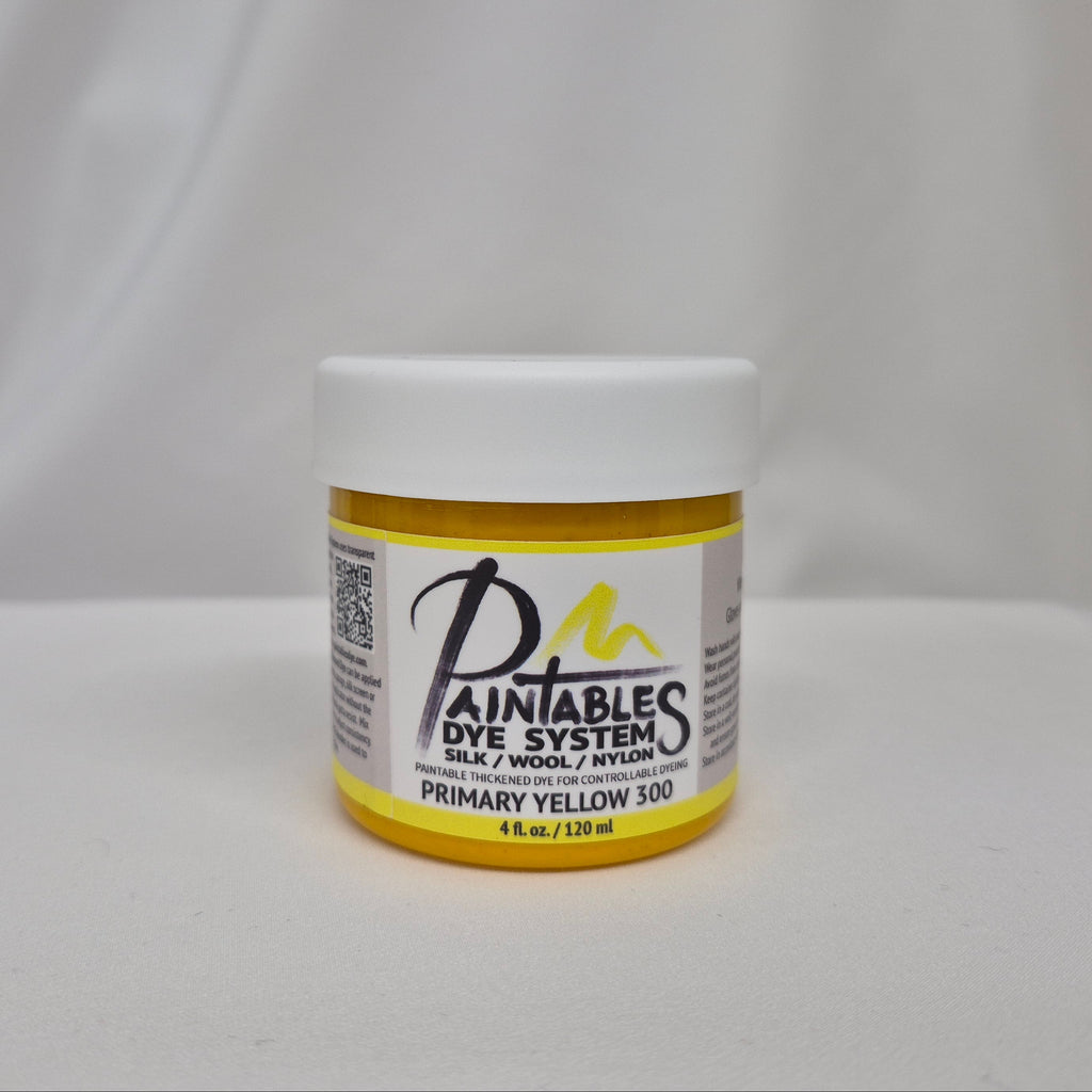 A jar of Paintable Dye System Primary Yellow 300 dye, featuring a white lid and a yellow label with black and white text, set against a draped white fabric background.