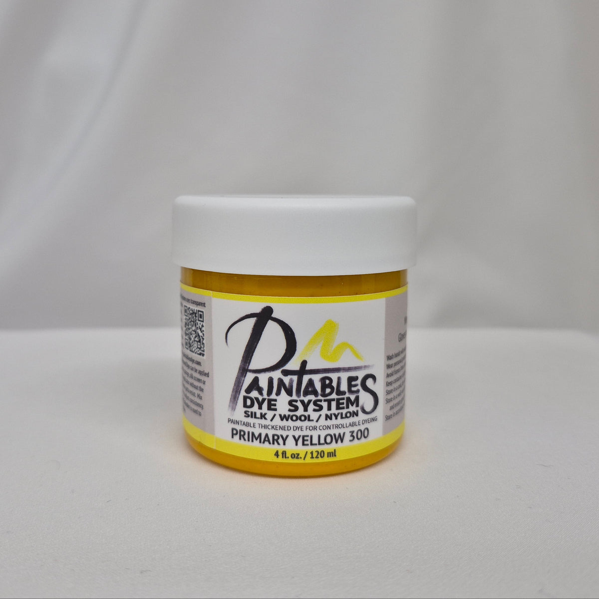 A jar of Paintable Dye System Primary Yellow 300 dye, featuring a white lid and a yellow label with black and white text, set against a draped white fabric background.