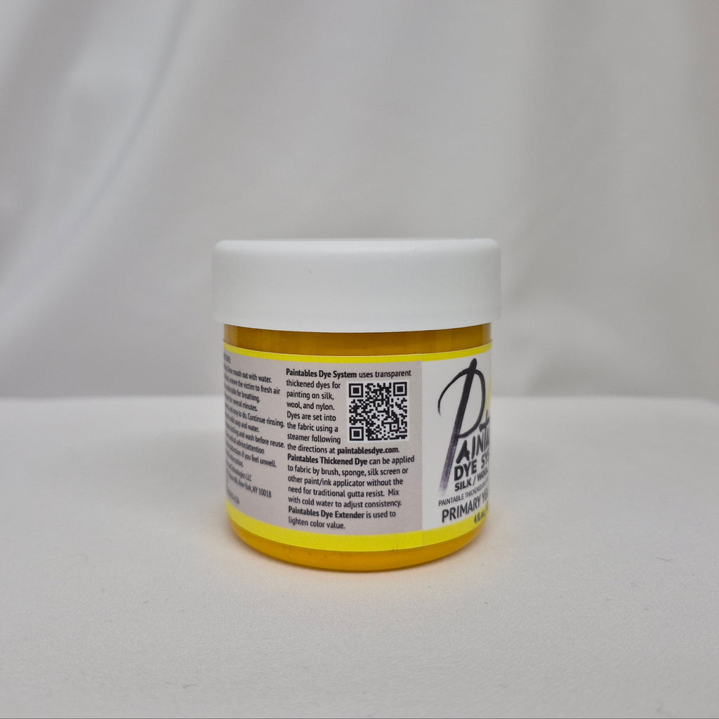 A small white plastic jar with a yellow lid and a white label featuring black text and a QR code, set against a draped white fabric background.